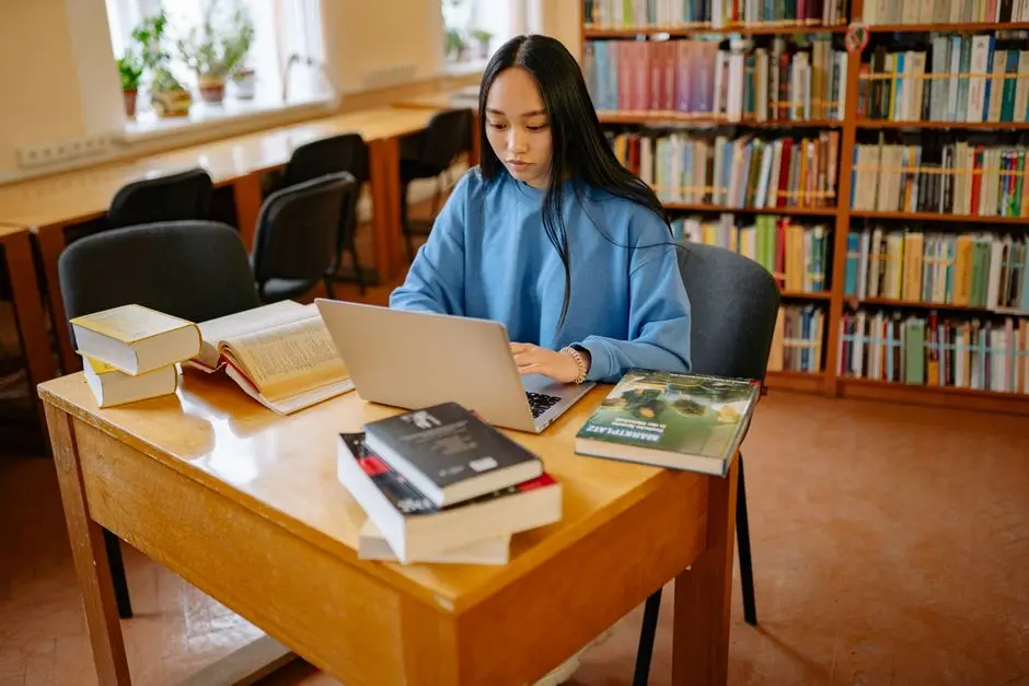 Mahasiswa sedang belajar menggunakan buku dan laptop